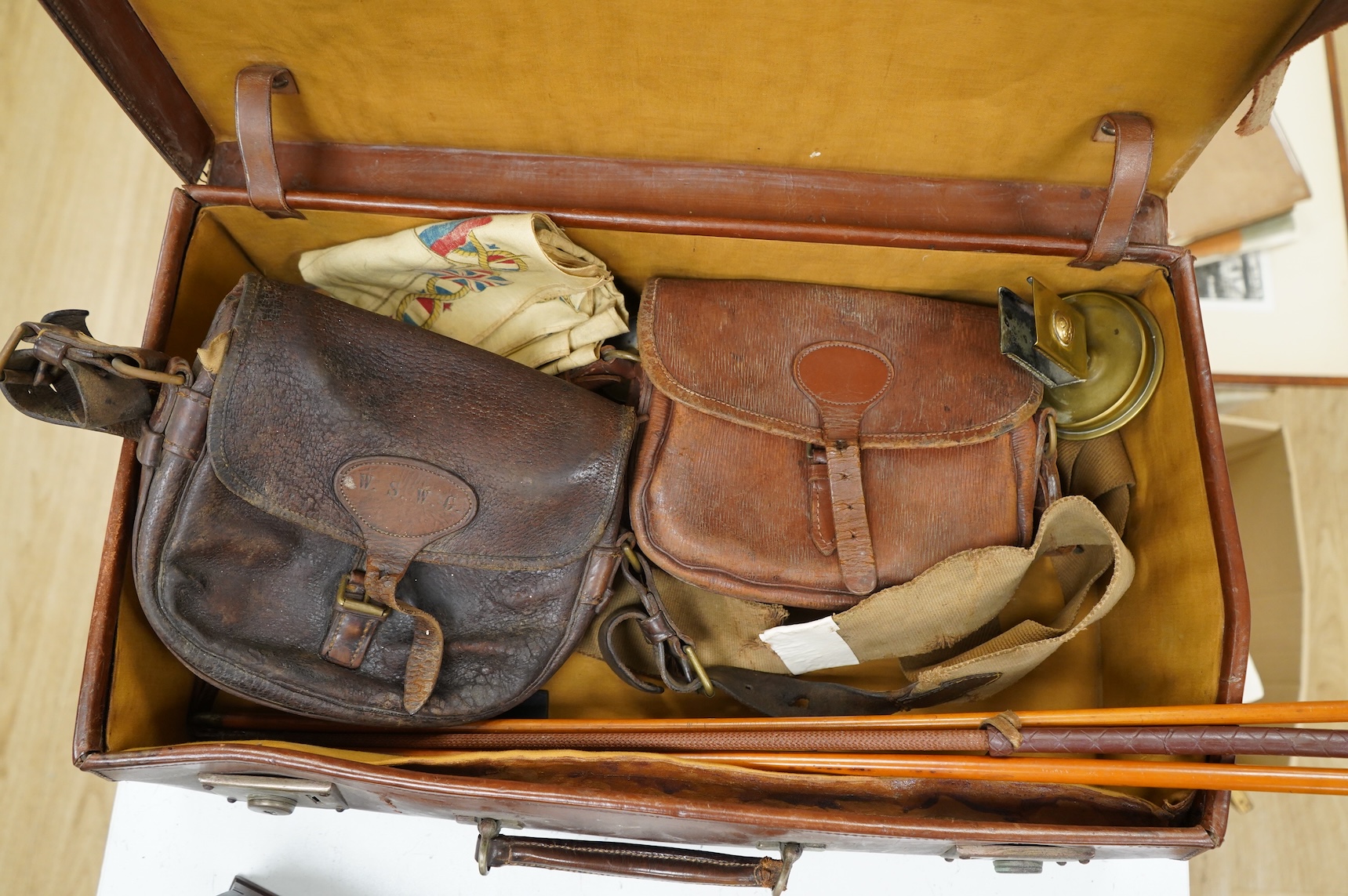A suitcase of military related items, including; a Manchester Guardian issued early 20th century map of Europe printed on cotton, a First World War trench art match holder the base formed from a cartridge case, two swagg